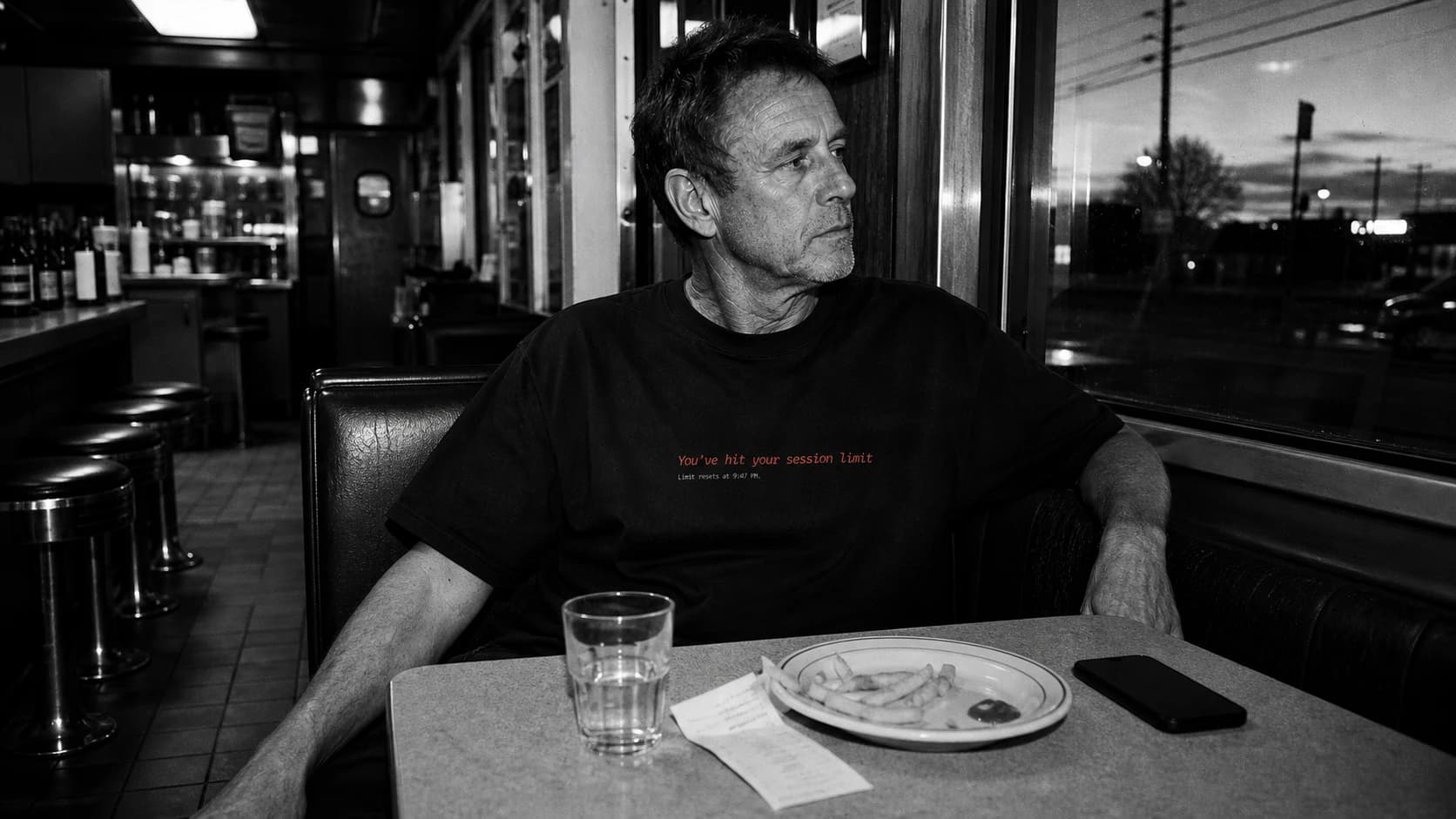 A man wearing a Mostly Human shirt in a diner at night