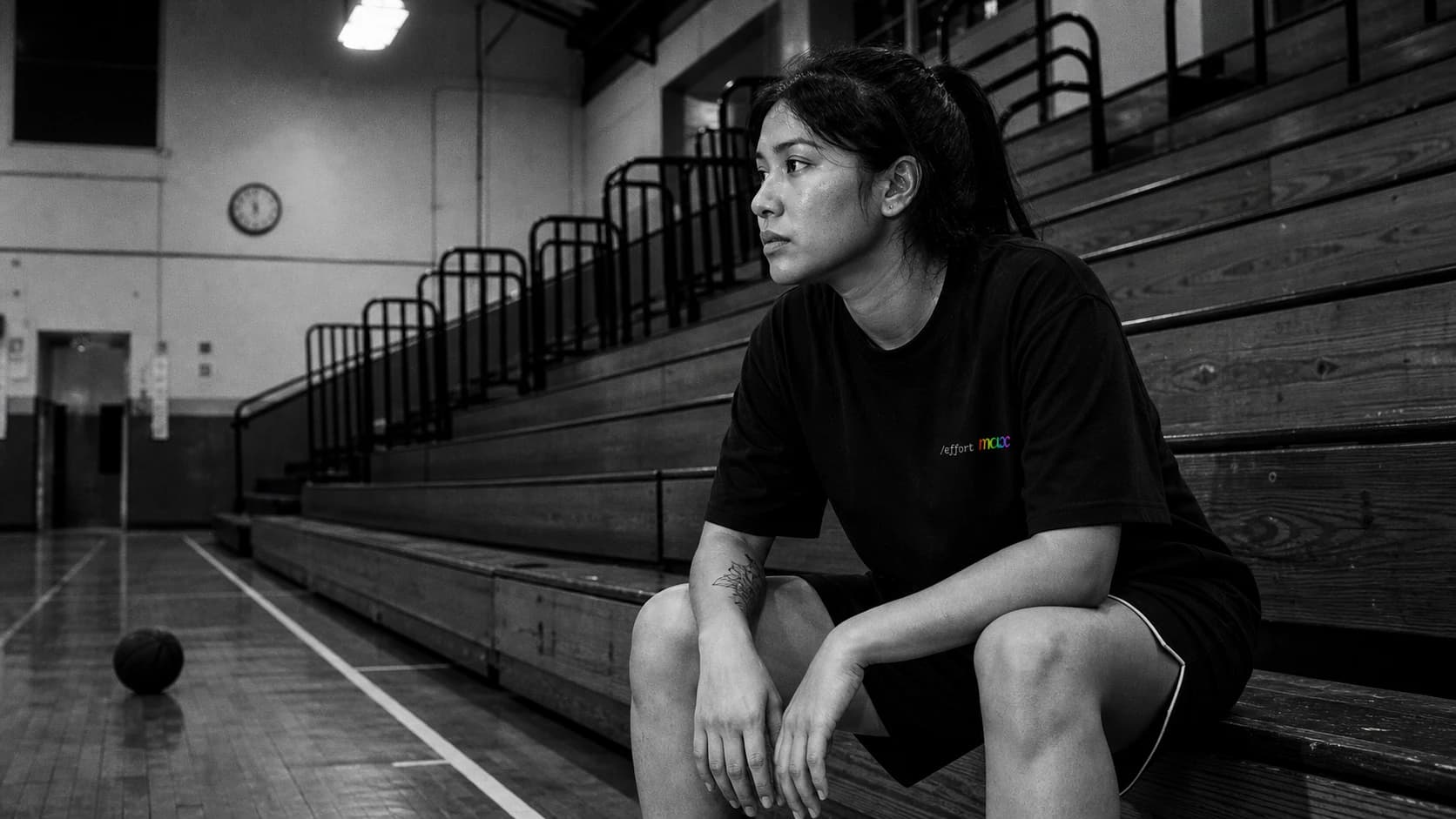 A woman wearing a Mostly Human shirt on community-gym bleachers